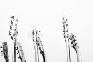 A group of guitars stand against a white wall.