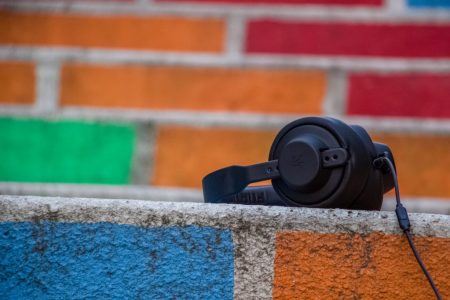 A pair of headphones sits on a colorful wall.